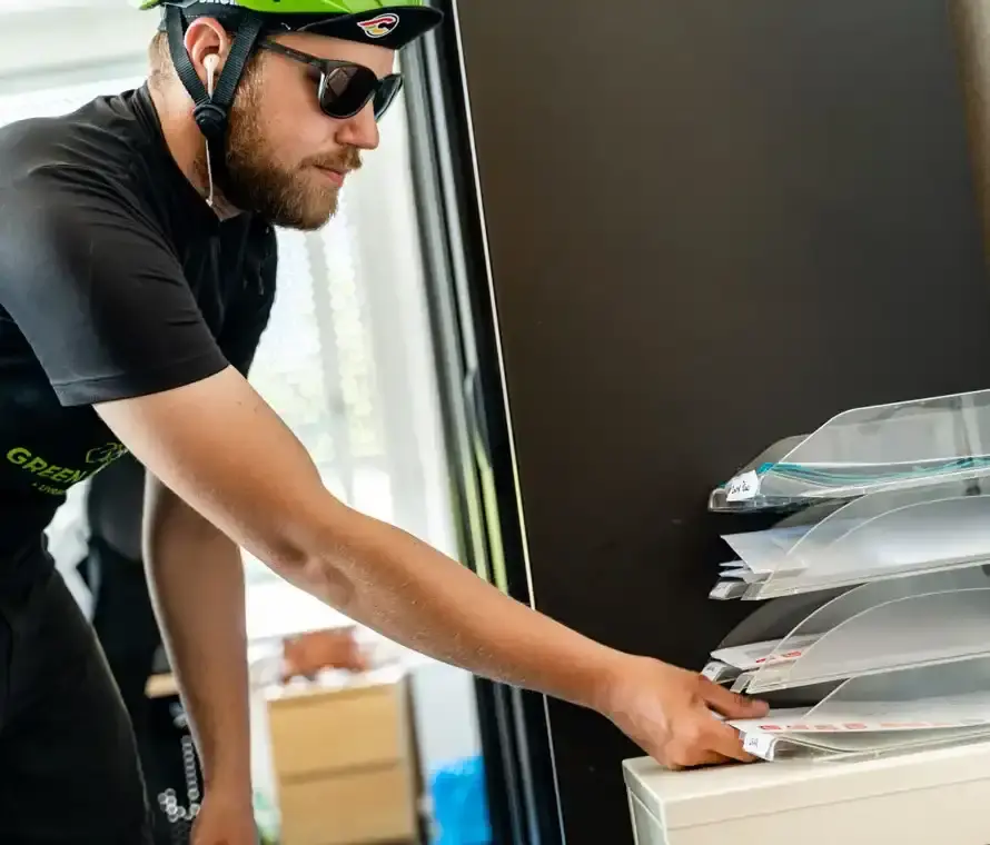Coursier à vélo collectant du courrier ou des colis dans une entreprise.