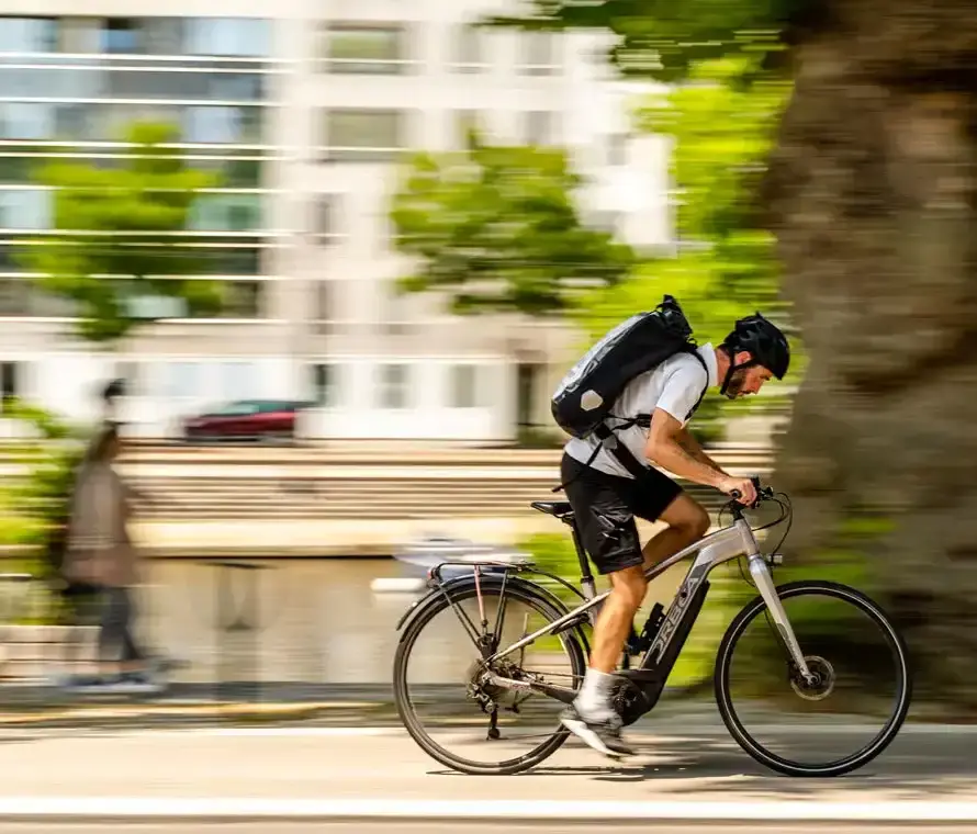 Coursier à vélo avec sac à dos, traversant une rue de Nantes, illustrant une livraison urgente.