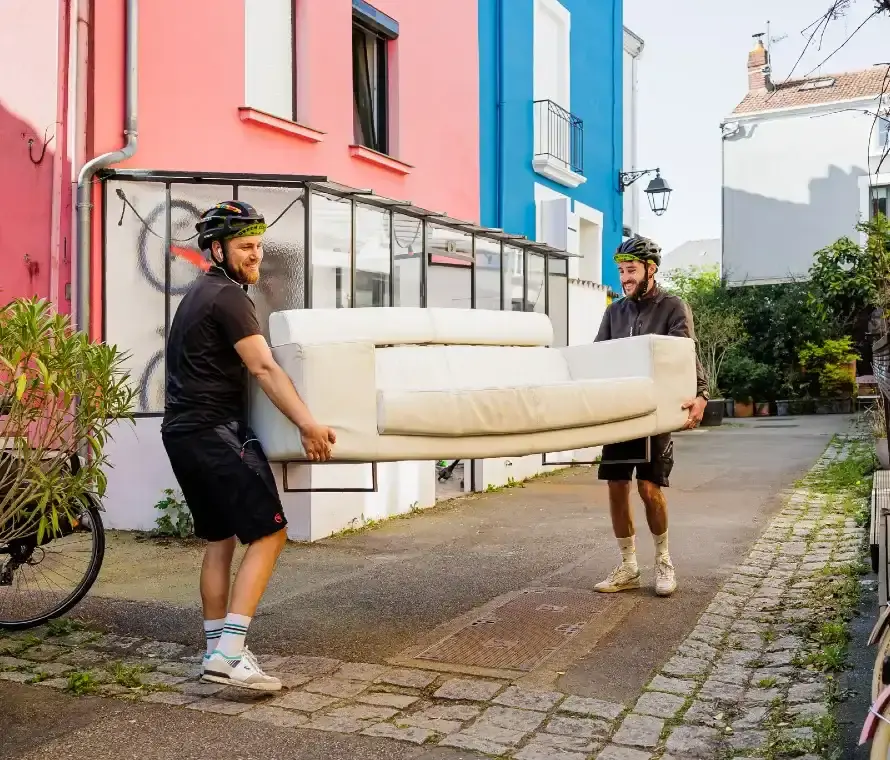 Deux coursiers livrant un canapé à domicile à Nantes avec un vélo cargo écologique.